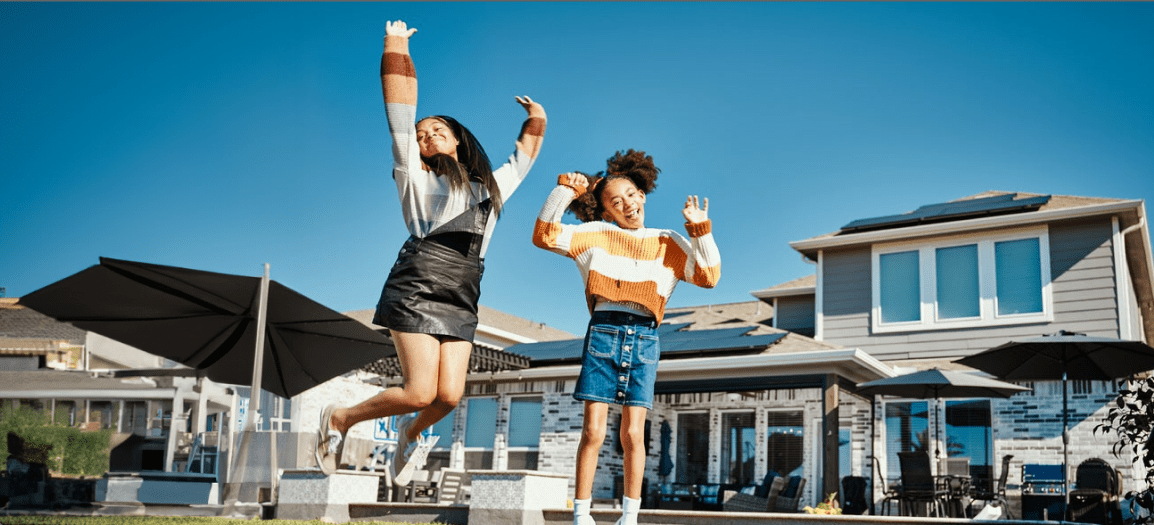 Children jumping for joy over solar panels for home use.